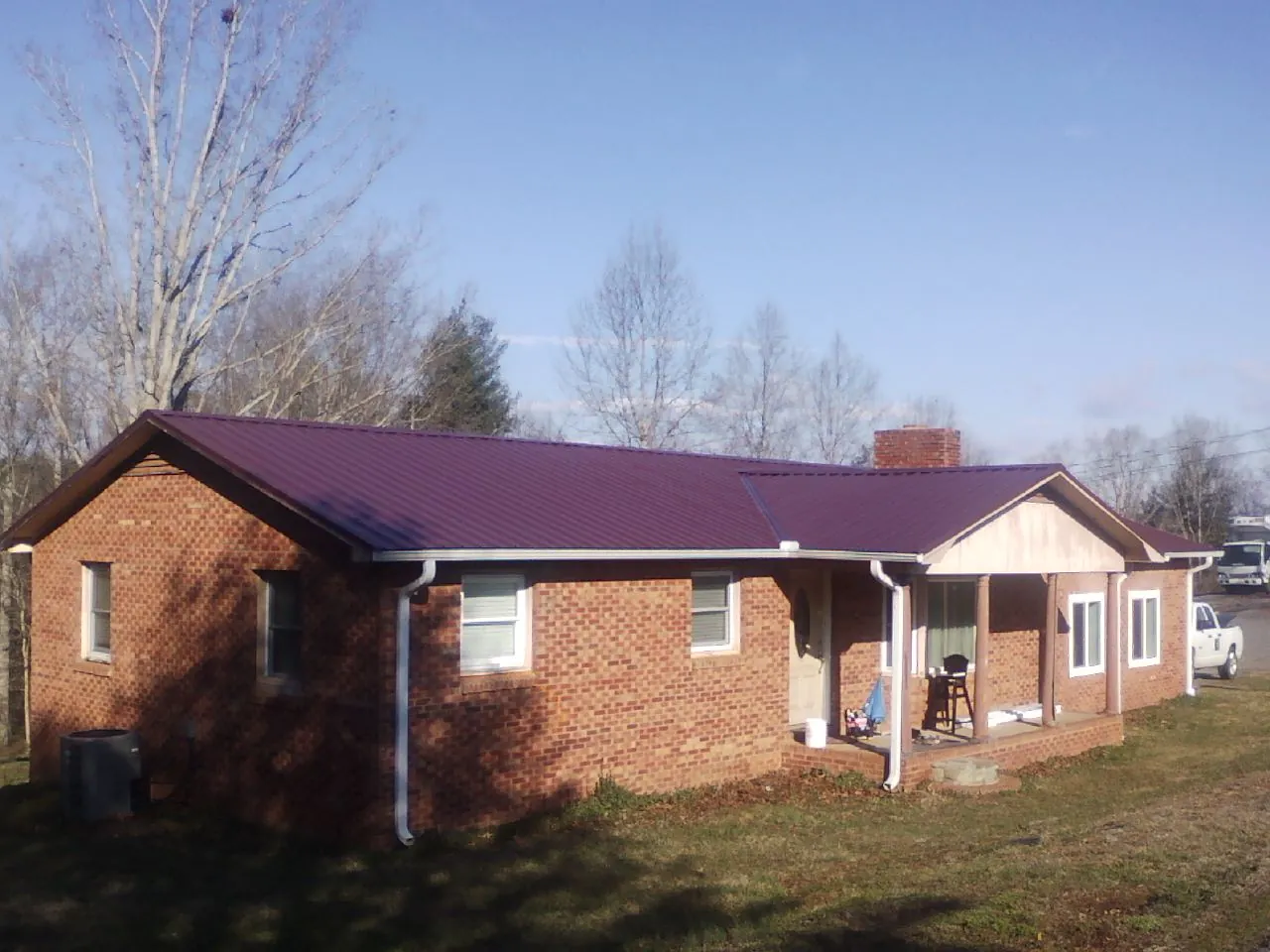 Burgundy metal roof on a brick ranch home with a new addition in Amboy